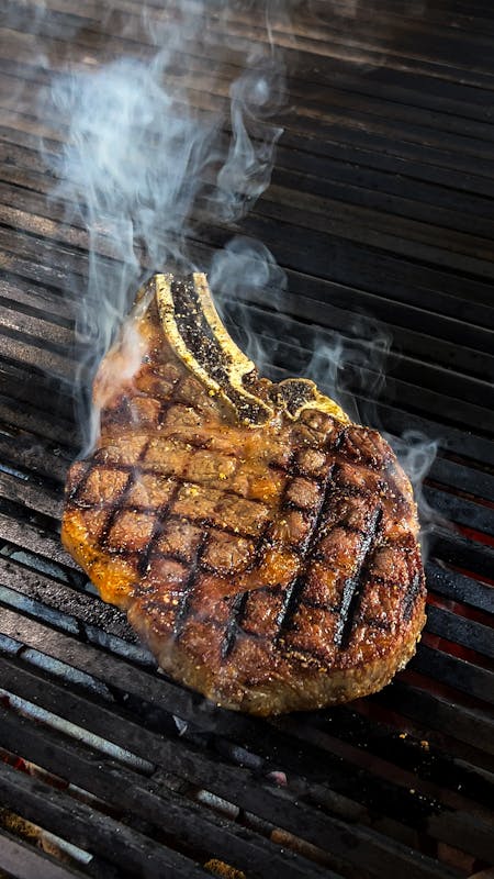 Smoky steaks seasoned with BBQ rub on grill grates