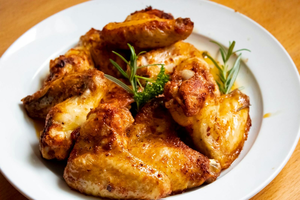 Crispy golden-brown smoked chicken wings served on a white plate with rosemary