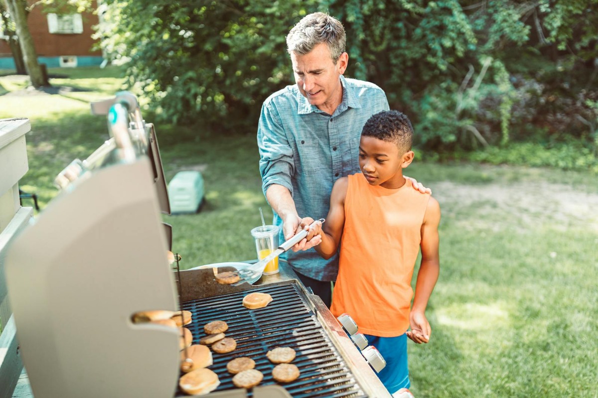 Father and son bonding over BBQ grill in sunny backyard - perfect for Father's Day