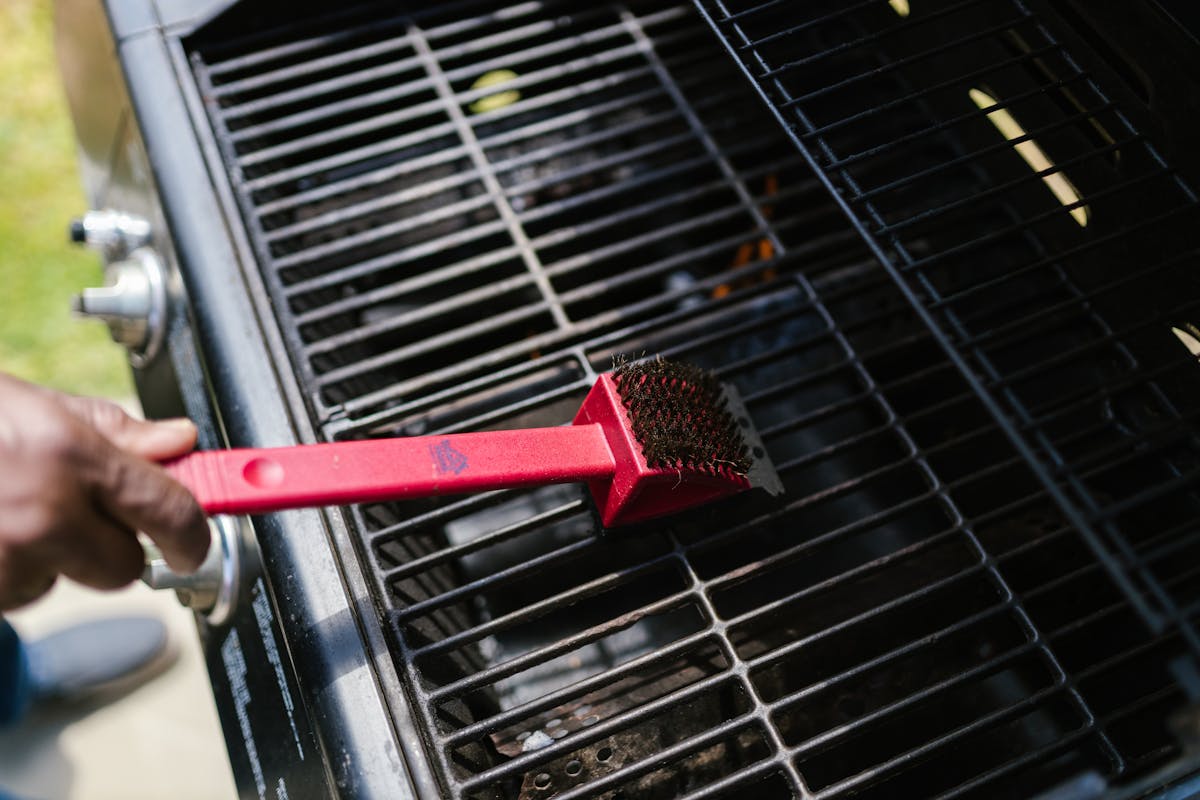 Cleaning barbecue grill grates with a red grill brush