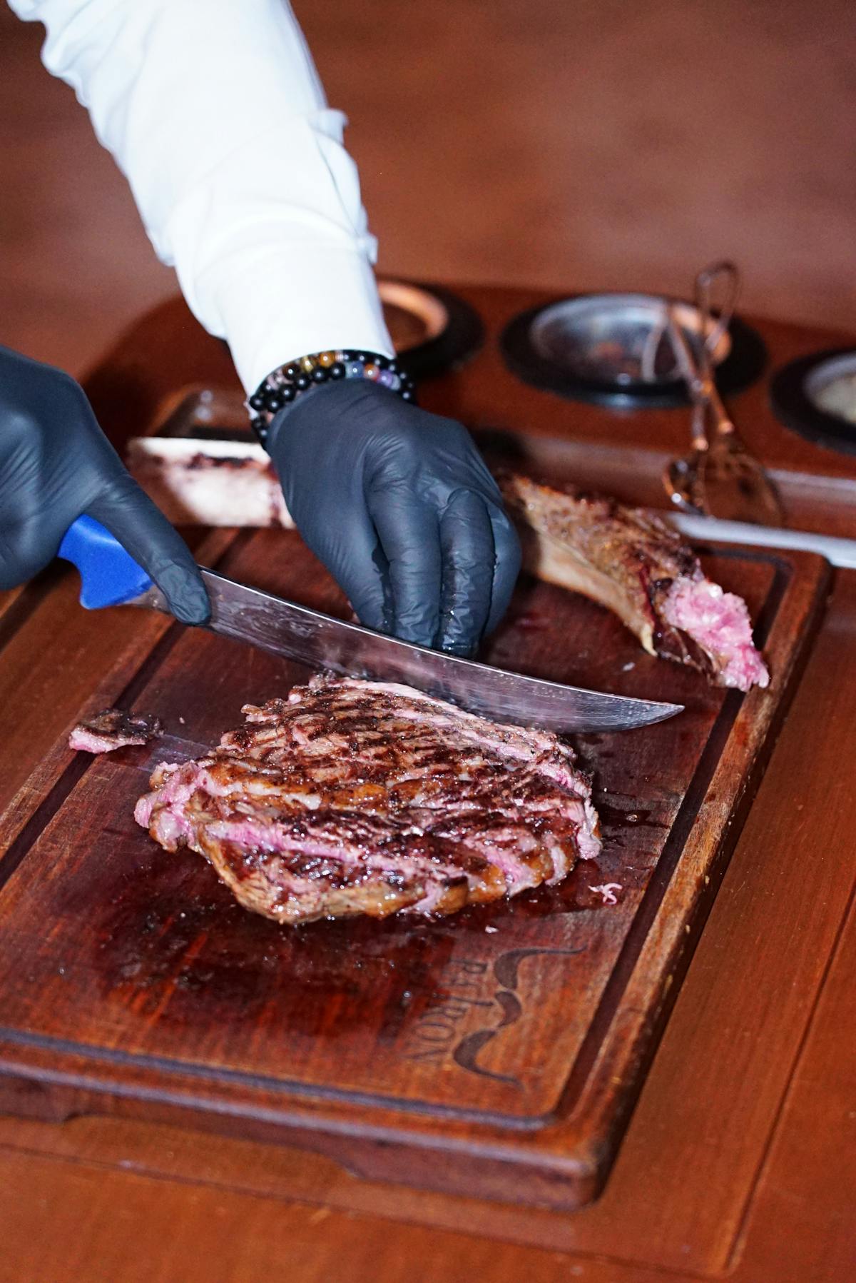 Chef slicing a grilled ribeye steak showing pink medium-rare interior