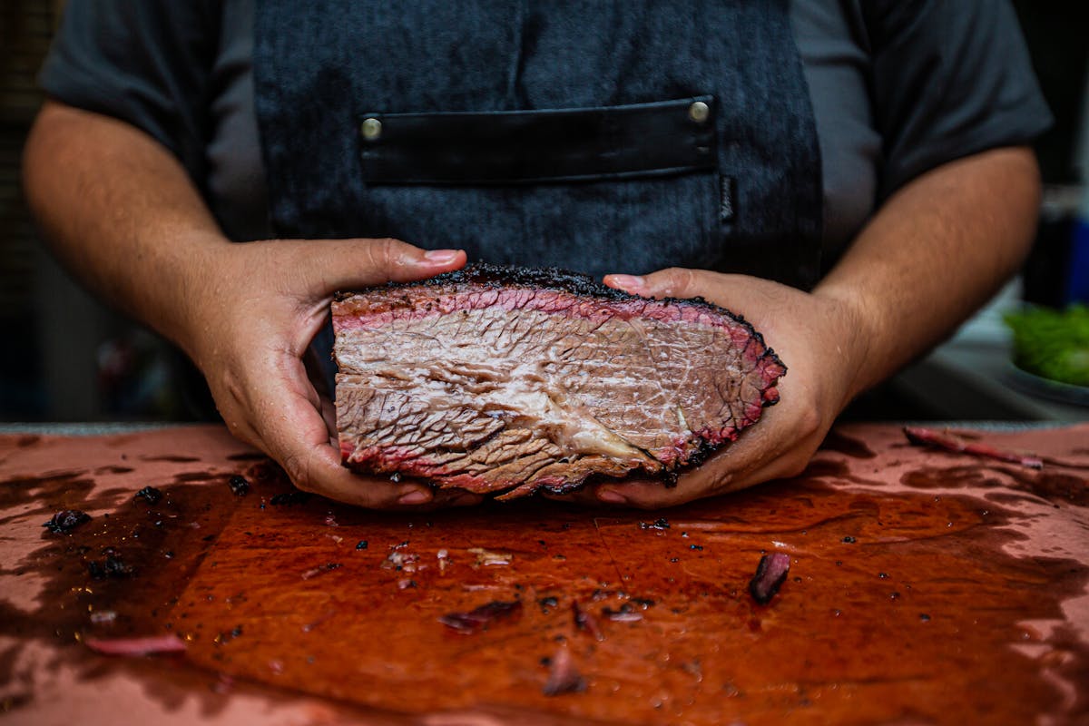 Pitmaster holding a smoked brisket cross-section with pink smoke ring