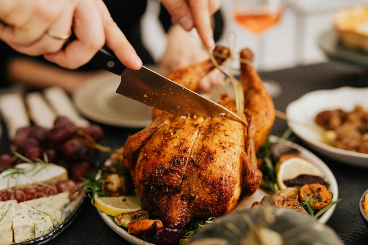 Golden-brown smoked turkey being carved at a holiday dinner table with sides