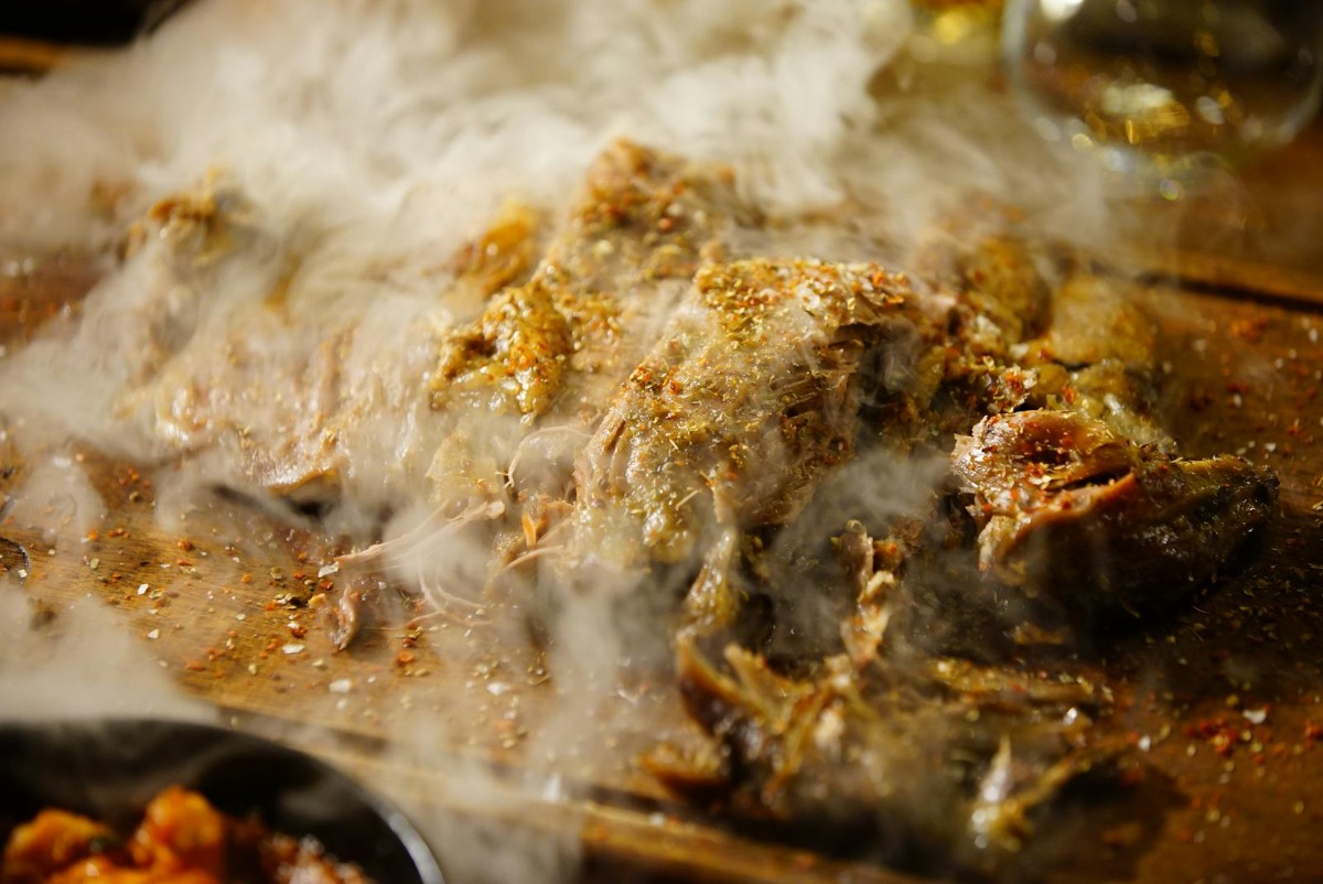 Hot steaming smoked pork shoulder on a cutting board fresh from the smoker