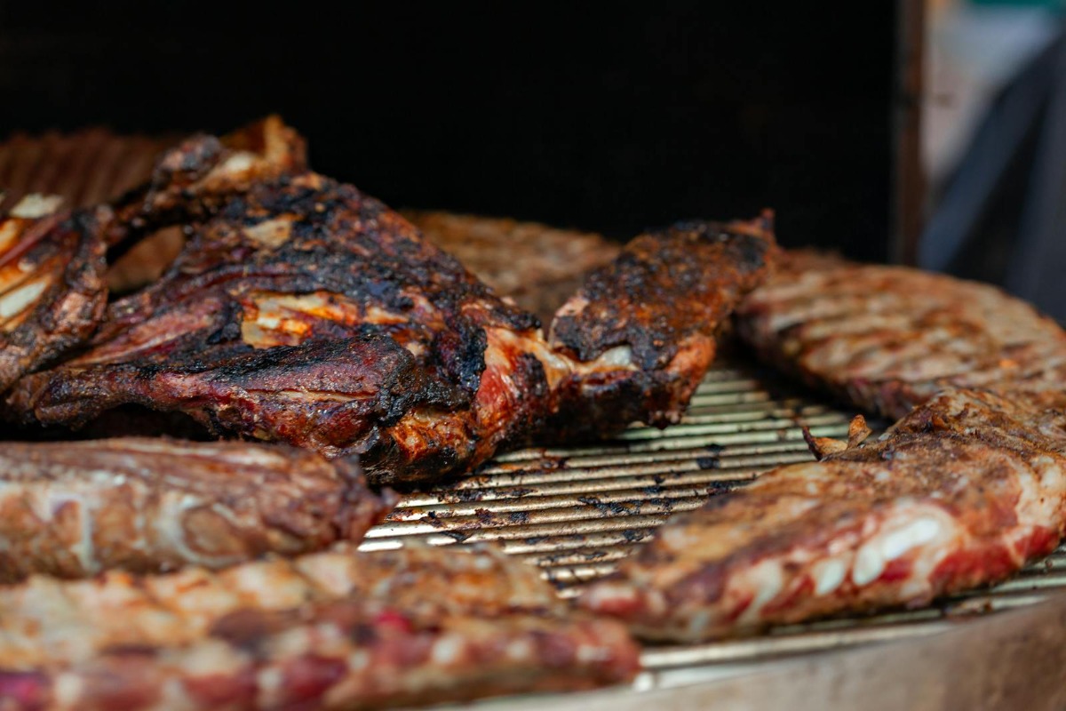 Variety of meats smoking on a grill grate