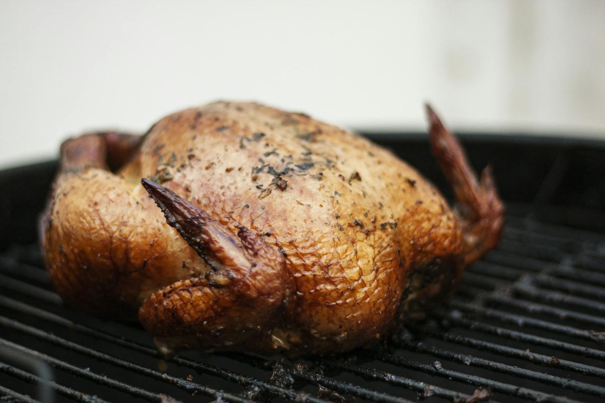 Whole smoked chicken with golden-brown crispy skin on a grill
